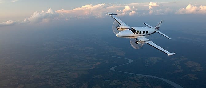 A small plane flying over the ocean in the sky.