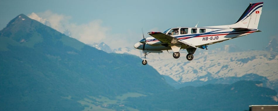 A small airplane flying over the mountains in the sky.